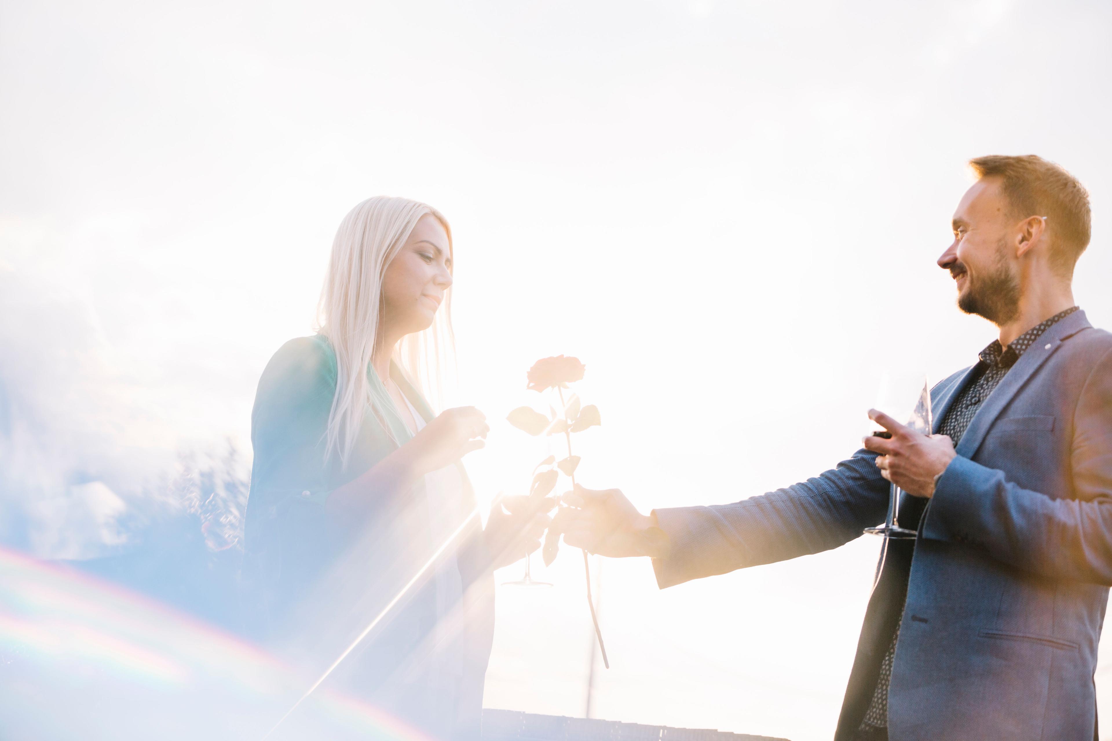 man-holding-wineglass-giving-rose-her-girlfriend-bright-sunlight.jpg